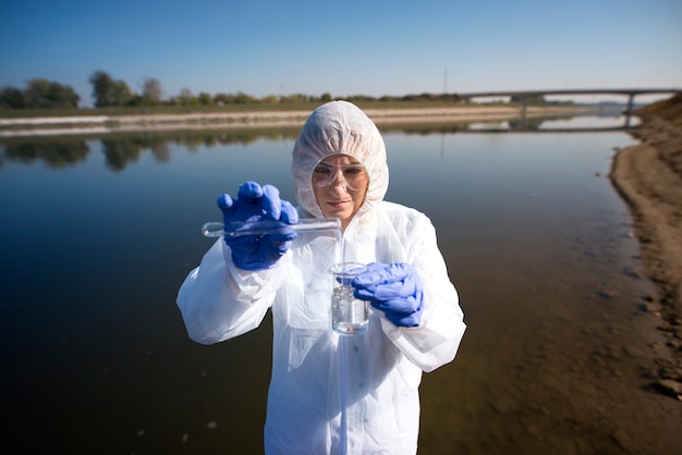 Free photo close up view of ecologist sampling water from the river with test tube