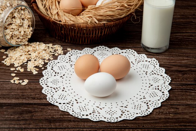 Close-up view of eggs on paper doily surface with oat flakes and milk on wooden background