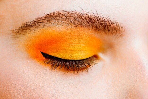 Close-up view of eye with yellow and orance make-up