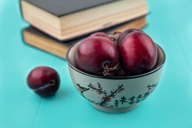 Close-up view of flavor king pluots in bowl with closed books on blue background