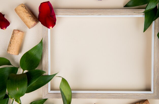 Close-up view of frame with corks on white decorated with leaves and flower petals with copy space