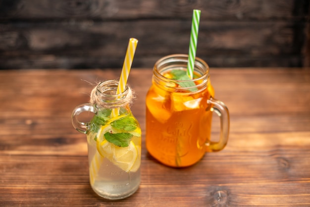 Close up view of fresh detox water and fruit juice served with tubes on a brown background