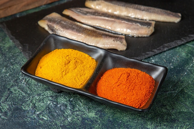 Free photo close up view of fresh raw chopped fish on black wooden cutting board spices on mix colors surface