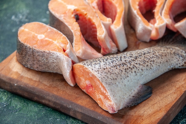 Free photo close up view of fresh raw fishes on brown wooden cutting board on dark mix colors table with free space