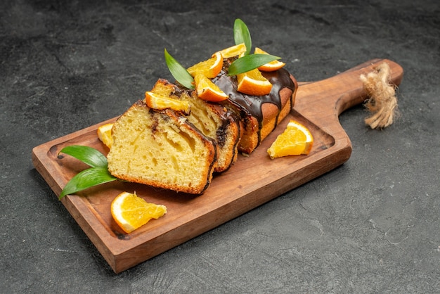 Close up view of freshly baked soft cake slices on wooden cutting board on dark table