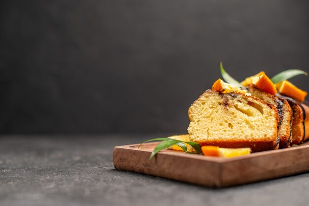 Close up view of freshly baked soft cake slices on wooden cutting board on dark table