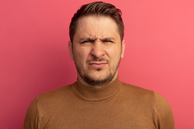 無料Photo 眉をひそめている若いブロンドのハンサムな男のクローズアップビュー