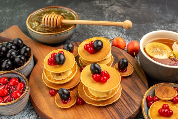 Close up view of fruit pancakes served with honey a cup of tea