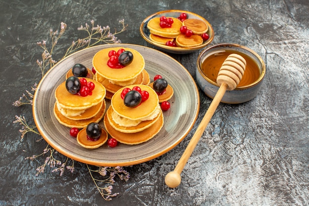 Close up view of fruit pancakes on a small and large plate with honey