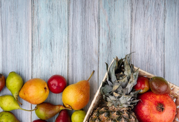 バスケットと木製の表面にパイナップルザクロ桃プラムとして果物のクローズアップ表示