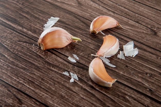 Close-up view of garlic cloves with skin on wooden background with copy space