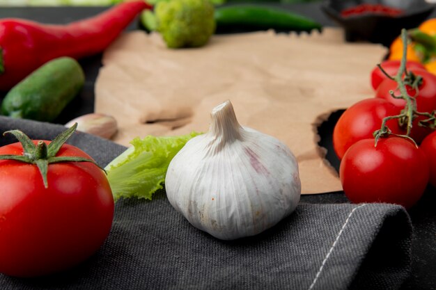 Close-up view of garlic with tomato and other vegetables on cloth surface