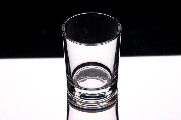 Close up view of glass cup on white table on dark background with free space