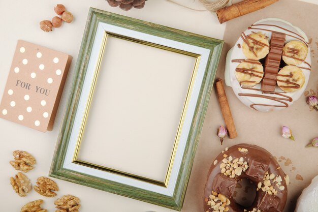 Close-up view of green frame with cinnamon cookies nuts on white with copy space