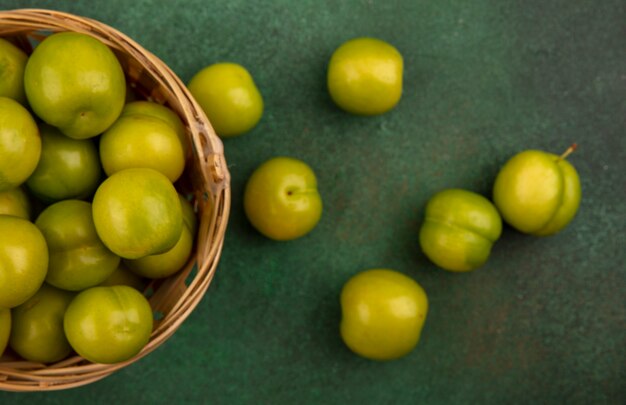 Close-up view of green plums in basket and on green background