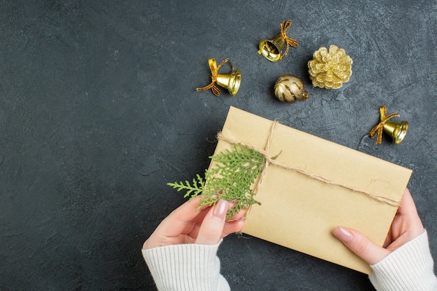 Close up view of hand holding gift box and decoration accessories on dark background