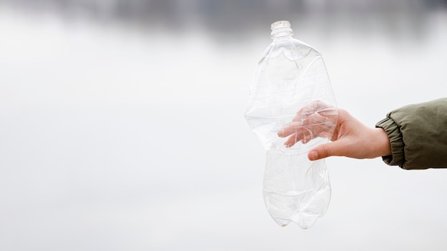 Крупным планом вид руки, держащей пластиковую бутылку