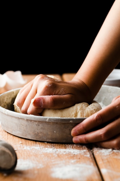 Close-up view of hand making dough in a tray