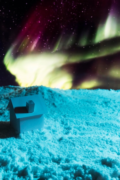 Close-up view of house on snow with aurora borealis