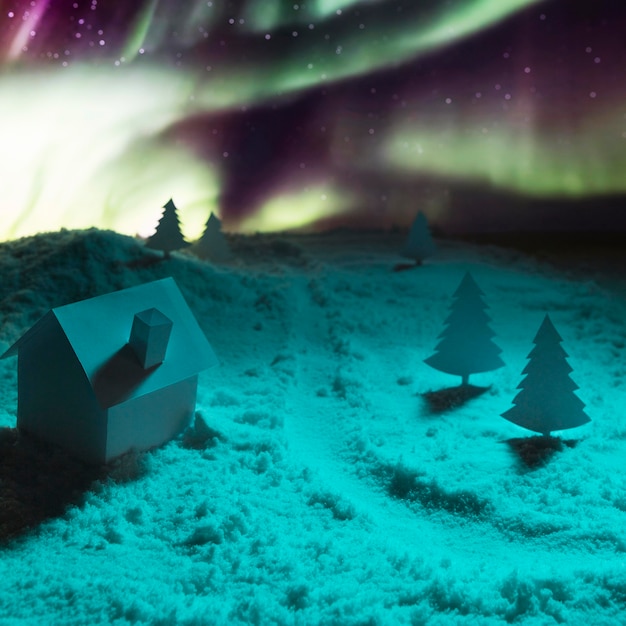 Vista ravvicinata della casa sulla neve con aurora boreale