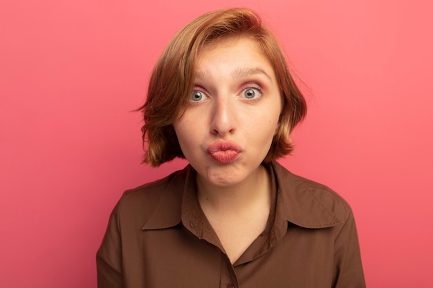 Free photo close-up view of impressed young blonde girl looking  doing kiss gesture isolated on pink wall