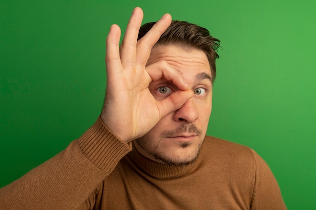 Close-up view of impressed young blonde handsome man doing look gesture