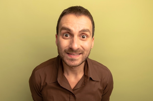 Free photo close-up view of impressed young caucasian man looking at camera smiling isolated on olive green background with copy space