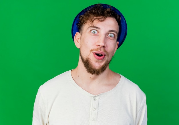 Free photo close-up view of impressed young handsome slavic party guy wearing party hat looking at camera isolated on green background