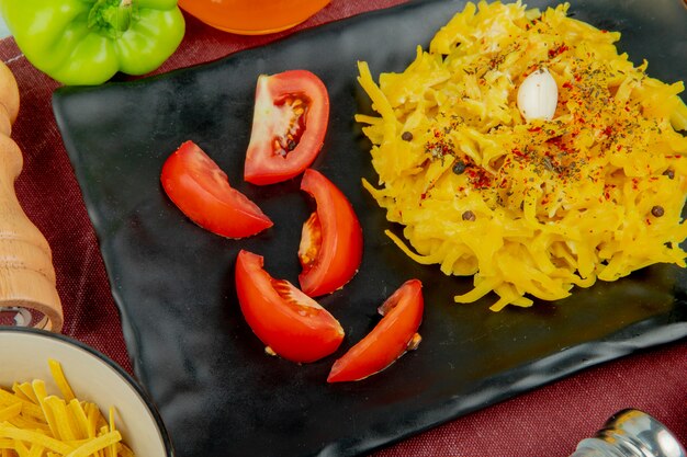 Close-up view of macaroni pasta and sliced tomato in plate with pepper tagliatelle macaroni salt on bordo cloth