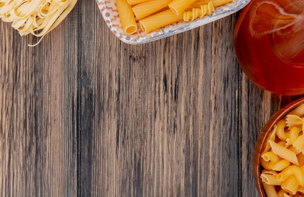 Close-up view of macaronis as tagliatelle ziti and other types with melted butter on wooden table with copy space