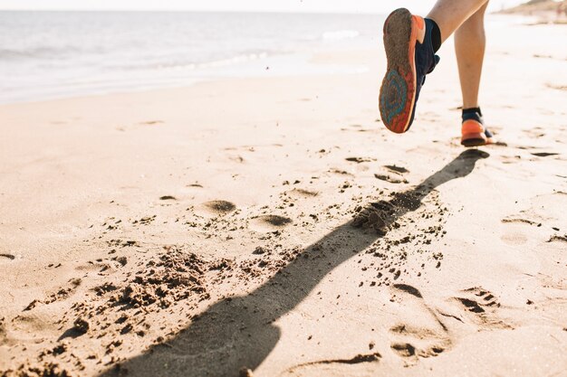 Close up view of man jogging on the sand