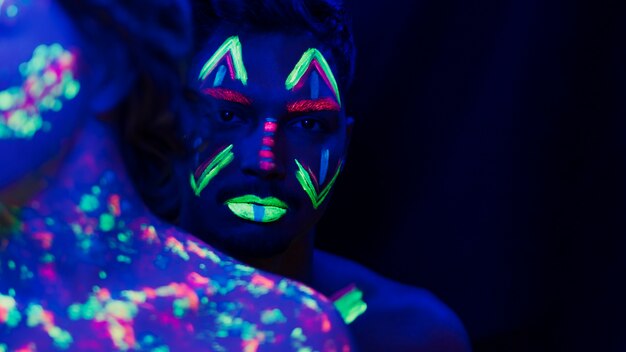 Close-up view of man with colorful fluorescent make-up