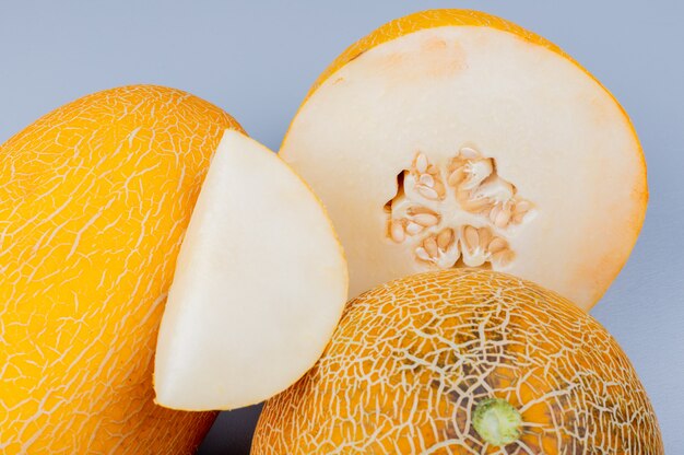 Free photo close-up view of melon slice with cut and whole ones on bluish gray background