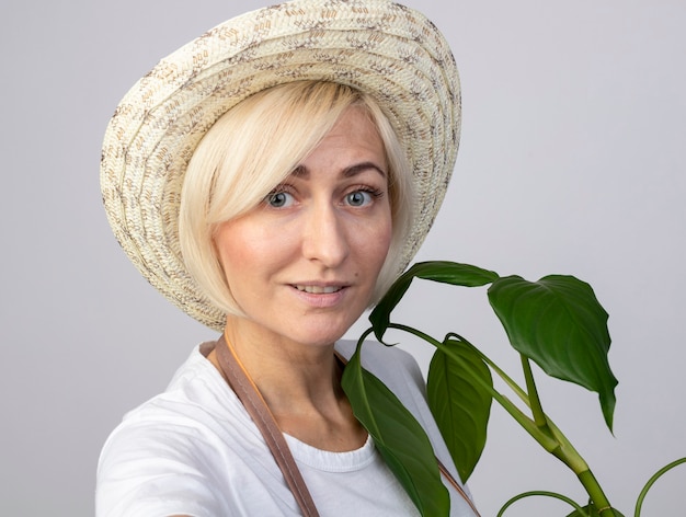 Бесплатное фото Крупным планом довольная блондинка среднего возраста садовница в униформе в шляпе