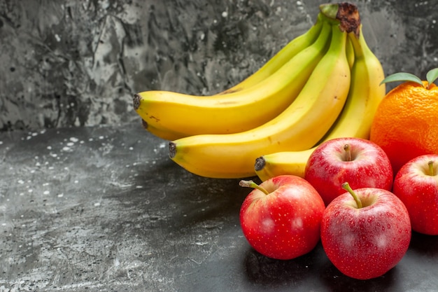 Free photo close up view of organic nutrition source fresh bananas bundle and red apples an orange on dark background