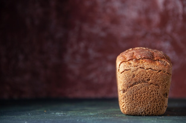 Close up view of packed black bread on the left side on maroon distressed background with free space