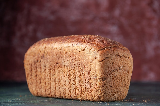 Close up view of packed black bread on maroon distressed background with free space