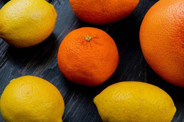 Close-up view of pattern of citrus fruits as tangerine lemon orange on wooden background