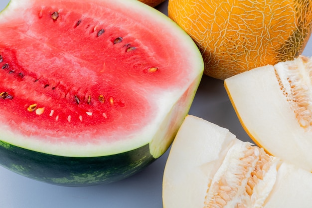 Close-up view of pattern of cut and whole fruits as watermelon and melon on bluish gray background