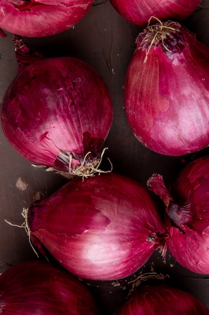 Close-up view of pattern of red onions on maroon background