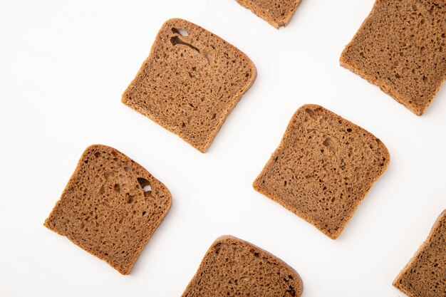 Close-up view of pattern of rye bread slices on white background with copy space