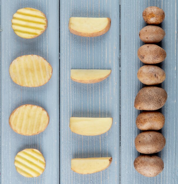 Close up view of pattern of sliced and whole potatoes on wooden background