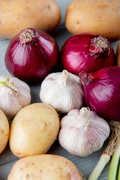 Close up view of pattern of vegetables as red onion garlic potato on wooden background