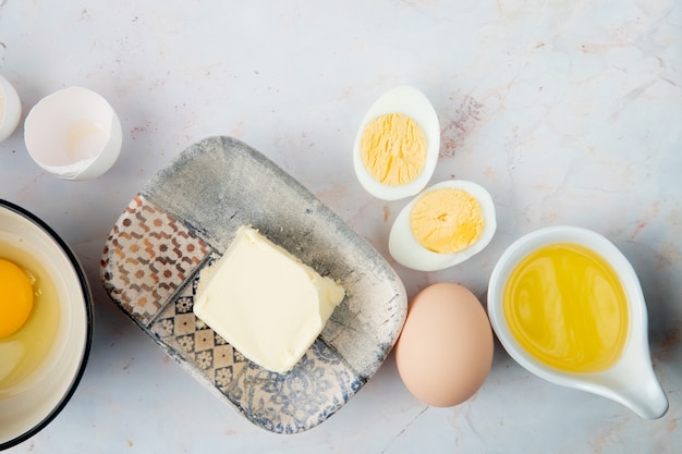 Close-up view of plate of butter and eggs with melted butter and eggshell on white background with copy space