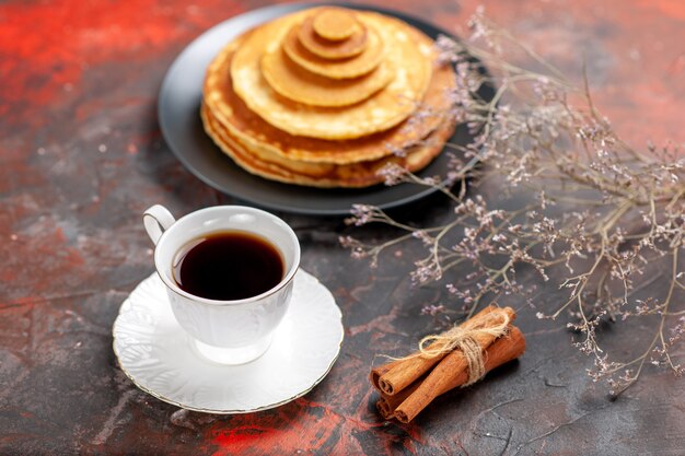 Close up view of pluffy pancakes and a cup of tea next to cinnamon lime