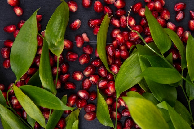 Close up view of pomegranate berries and leaves on black surface