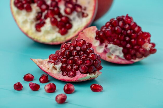 Close up view of pomegranate pieces and berries with half one on blue surface