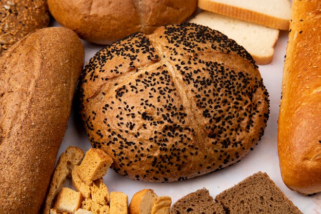 Close-up view of poppy seed cob with seeded baguette and bread pieces and other breads on white background