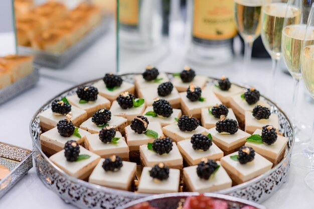 Close up view of portion beige colored mousses desserts decorated with blackberries