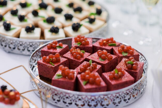 Крупным планом вид порционных муссовых десертов, украшенных красной смородиной